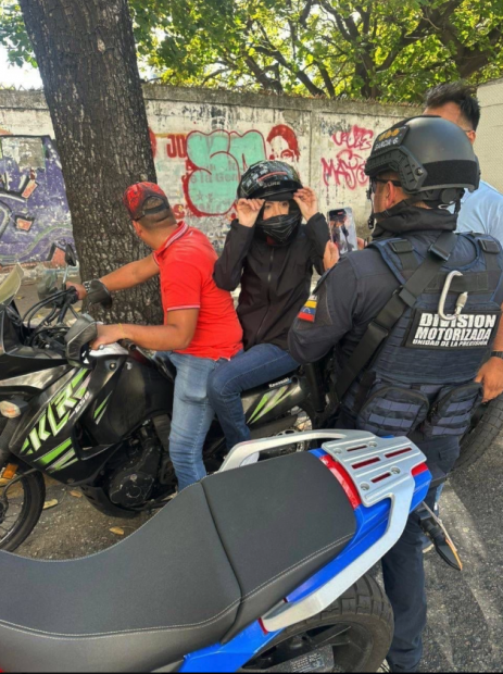 Imagen De María Corina Machado Siendo Grabada Por Un Oficial En Una Moto De Las Fuerzas De Seguridad De Maduro